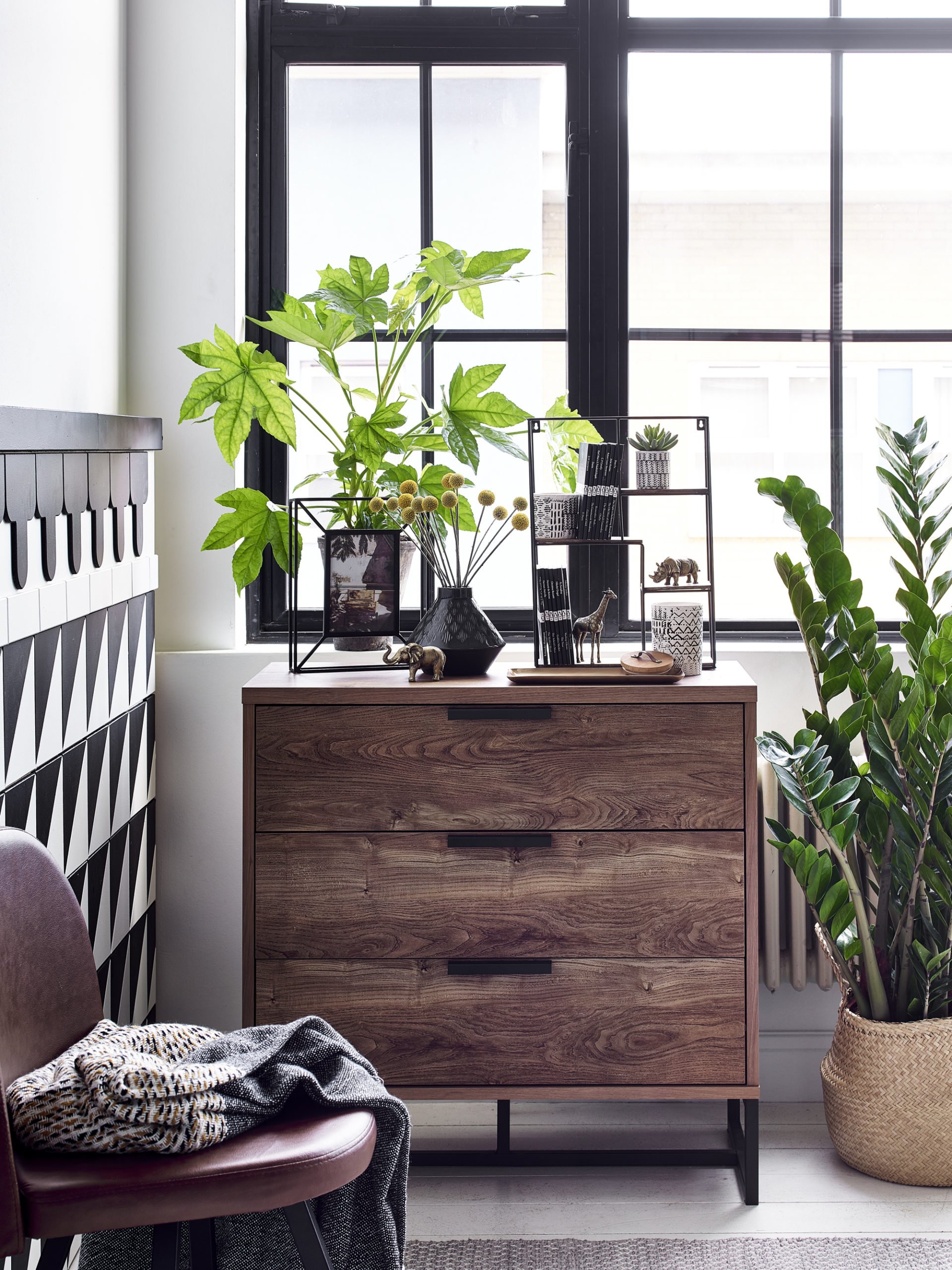 black and white living room with tiled walls lots of plants and baskets